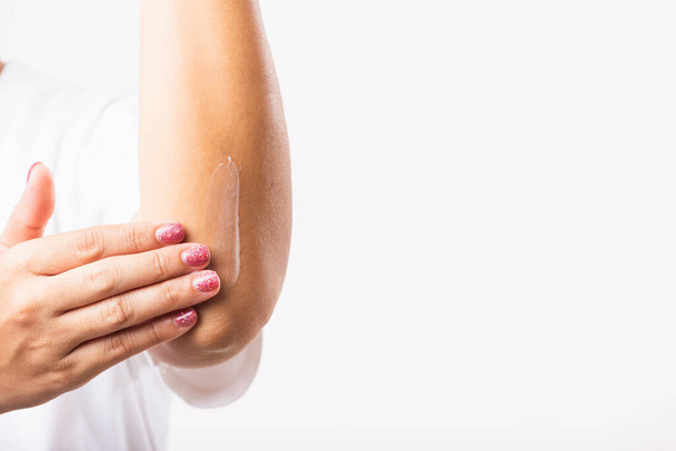 Closeup young Asian woman applies lotion cream on her elbow, studio shot isolated on white background, Healthcare medical and hygiene skin body care concept - Photo, Image