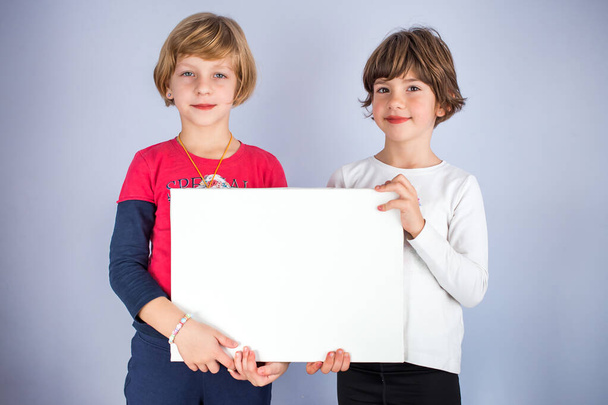 Two little girls hold empty white board. Copy space, space for writing - Photo, image