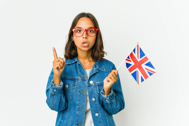 Mujer latina joven sosteniendo una bandera inglesa aislada sobre fondo blanco teniendo una idea, concepto de inspiración. - Foto, Imagen