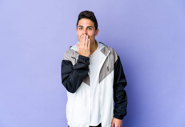 Young caucasian man isolated on purple background shocked, covering mouth with hands, anxious to discover something new. - Photo, Image