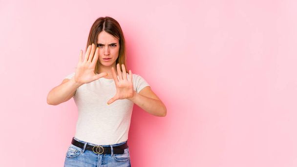 Young caucasian woman isolated on pink background rejecting someone showing a gesture of disgust. - Photo, Image