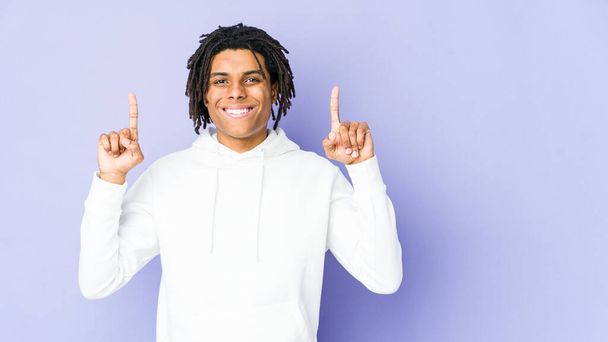 joven afroamericano rasta hombre indica con ambos dedos delanteros hacia arriba mostrando un espacio en blanco. - Foto, imagen