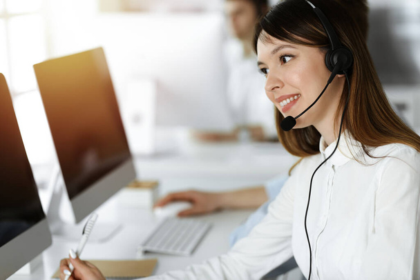 Asian woman working at customer service office. Business concept. Group of diverse operators at work in sunny call center. - Photo, Image