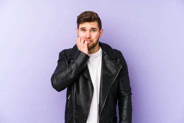 Young man isolated on purple background biting fingernails, nervous and very anxious. - Photo, Image