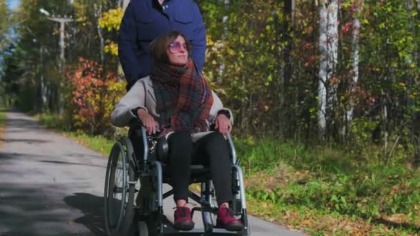 Man loopt met vrouw op rolstoel - Video