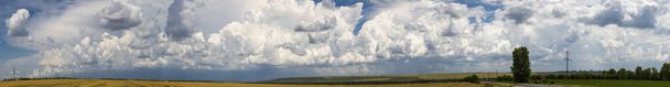Χωράφια σιταριού πριν τη βροχή. Cumuliform cloudscape στον γαλάζιο ουρανό. Ο ήλιος είναι κρυμμένος. Πανόραμα. - Φωτογραφία, εικόνα