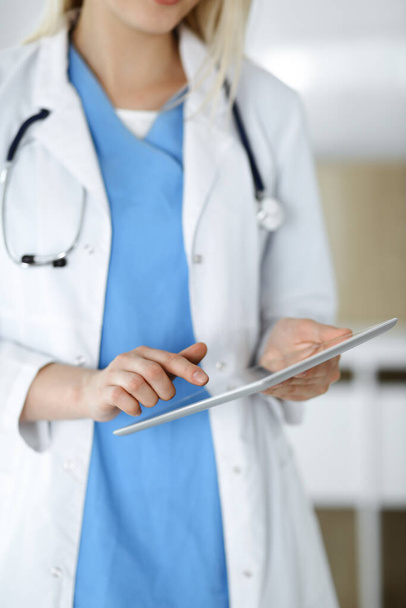 Unknown woman-doctor standing in clinic and using tablet pc, close-up. Data and best service in medicine and healthcare - Φωτογραφία, εικόνα