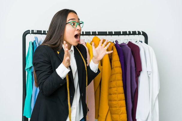 Mladý asijský designér žena izolovaný na bílém pozadí křičí nahlas, udržuje oči otevřené a ruce napjaté. - Fotografie, Obrázek