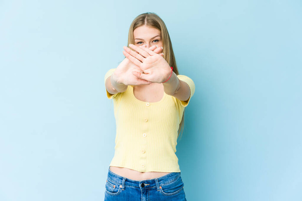 Fiatal szőke nő elszigetelt kék háttér csinál egy tagadás gesztus - Fotó, kép