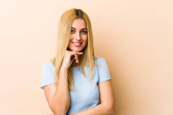 Young blonde caucasian woman smiling happy and confident, touching chin with hand. - Photo, image