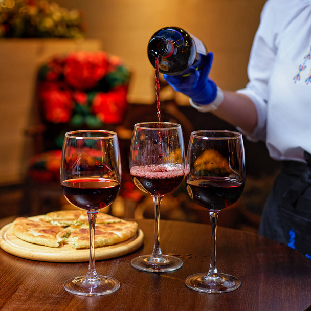 Close-up of waiter pouring wine into glasses in restaurant. Buffet table celebration of wine tasting. Nightlife - Valokuva, kuva