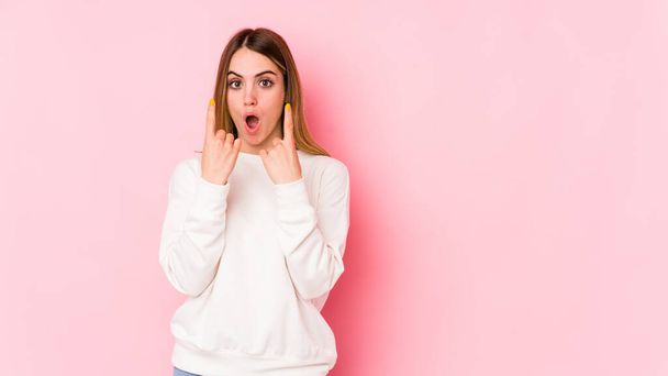 Young caucasian woman isolated on pink background pointing upside with opened mouth. - 写真・画像