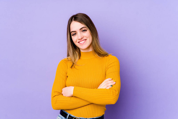 Young caucasian woman isolated on purple background who feels confident, crossing arms with determination. - Photo, Image