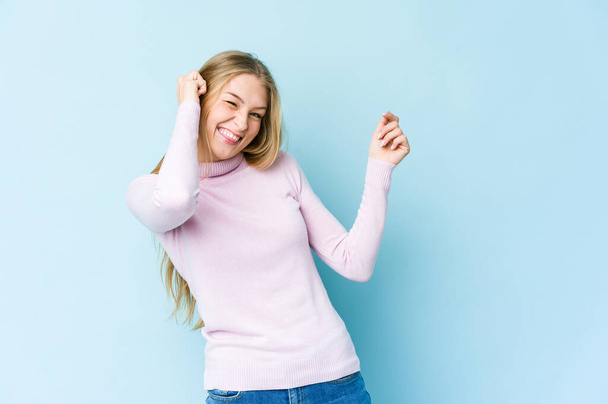 Young blonde woman isolated on blue background dancing and having fun. - Φωτογραφία, εικόνα