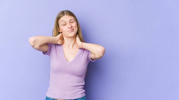 Mujer rubia joven aislada sobre fondo púrpura sufriendo dolor de cuello debido a un estilo de vida sedentario. - Foto, imagen