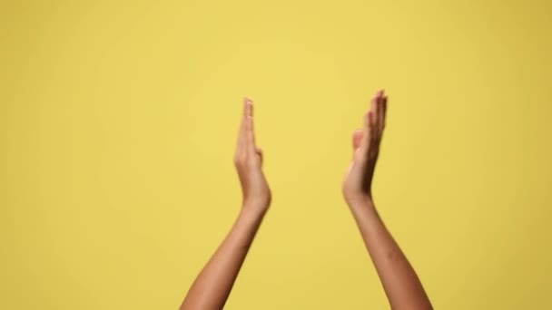dwie ręce klaszczące, wskazujące na kamerę, wskazujące na siebie i świętujące sukces na żółtym tle - Materiał filmowy, wideo