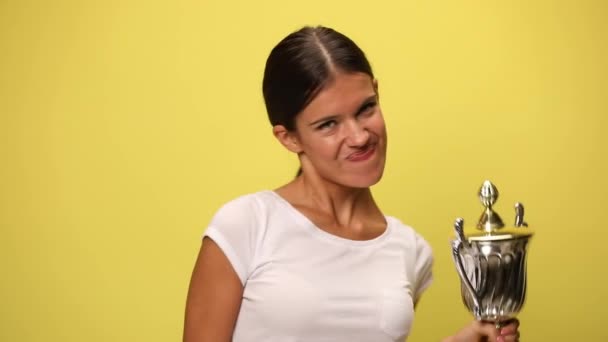 aantrekkelijke casual vrouw het verhogen van haar kopje en wijzen naar de camera op gele achtergrond - Video
