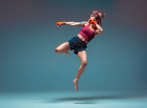 A young female fighter performs a jump kick. - Fotografie, Obrázek