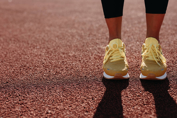 Stadyumdaki sarı spor ayakkabılı kadınların ayaklarını kapat. - Fotoğraf, Görsel