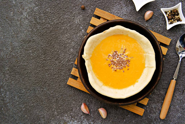 Pumpkin puree soup in an edible bread plate on a brown tray on a gray concrete background. Pumpkin recipes. Thanksgiving Day. - Фото, изображение