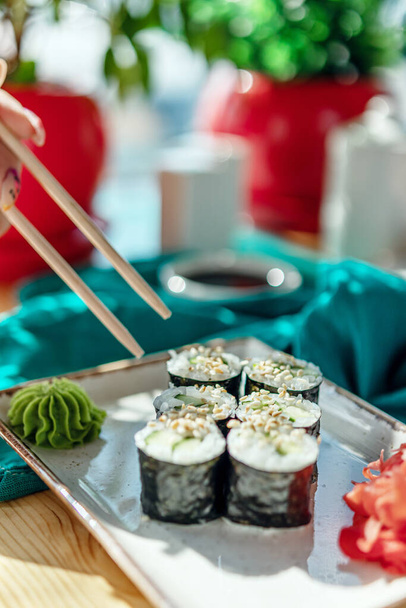 rollos de sushi con mariscos en la mesa palos en la mano - Foto, imagen