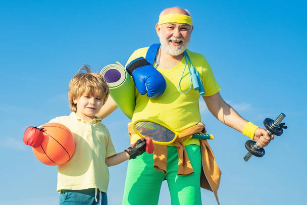 Sports for kids. Father and son sporting - family time together. Senior man and cute little boy exercising on blue sky background - isolated. - Foto, immagini