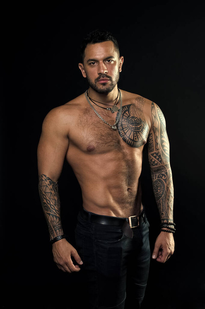 Macho sexy bare torso. Fit model with tattoo art skin. Sportsman or athlete with beard and hair. Sport and fitness. Masculinity. Muscular torso. Jewelry for real men. Bearded man with tattooed torso - Φωτογραφία, εικόνα