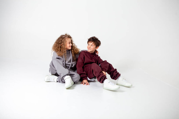 curly long-haired girl and boy in tracksuits - Foto, afbeelding