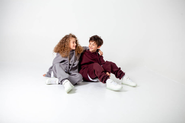 curly long-haired girl and boy in tracksuits - Zdjęcie, obraz