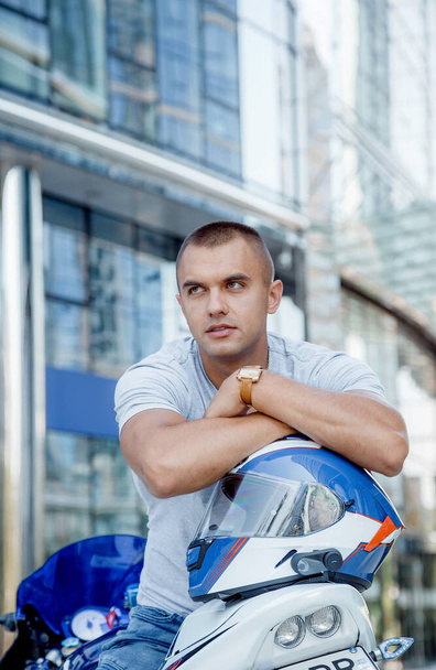 Young man on a sports motorcycle. The guy is sitting on a motorcycle. Motorcyclist. Male portrait - Photo, Image