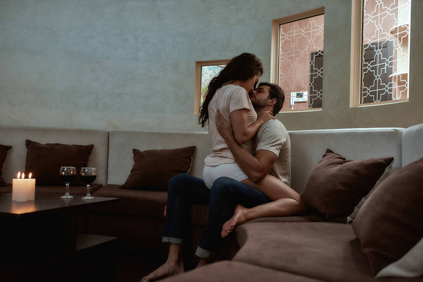 Passion. Young sexy man and woman are kissing before having sex on the couch - Fotografie, Obrázek