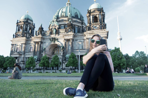 Pretty gil sitting in front of Berlin Cathedral doing selfie - 写真・画像