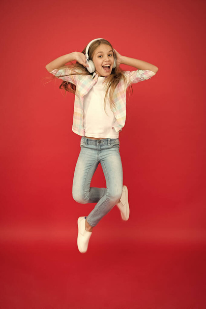 I believe i can fly. Girl listening music modern gadget. Kid happy with wireless headset dancing jumping. Stereo headphones. Kid using modern technology. Modern child. Perfect sound. Never ending joy - Foto, Imagen