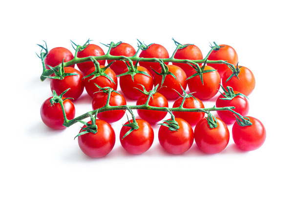 Deux fines branches vertes avec des grappes de petites tomates cerises rouges isolées sur un fond blanc - Photo, image