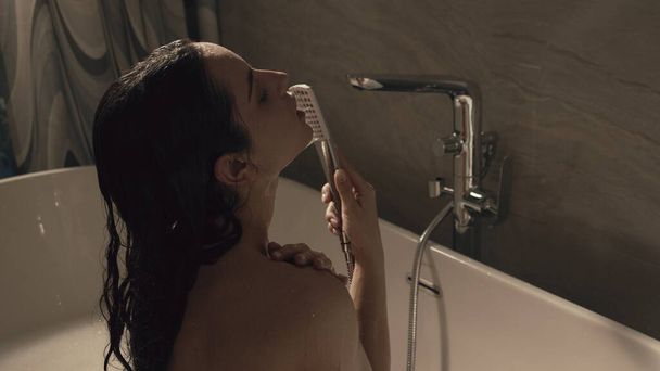 Naked girl taking shower in bathroom. Slim woman enjoying water treatments home - Фото, зображення