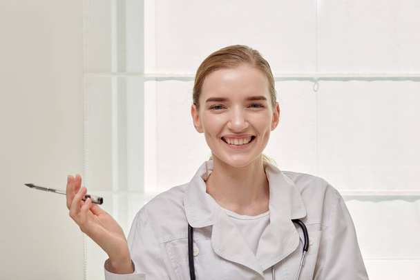 Portrait d'une jeune femme médecin souriante en manteau médical blanc. - Photo, image