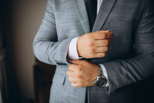 people, business, fashion and clothing concept - close up of man dressing up and fastening buttons on shirt at home. - 写真・画像