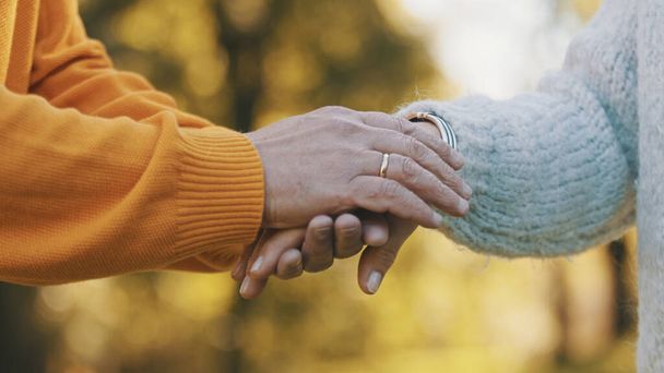 Sulje ryppyiset kädet. Onnellinen pariskunta halaamassa puistossa. Vanhempi mies flirttailee iäkkään naisen kanssa. Romantiikkaa vanhuudessa tanssimassa syyspäivänä - Valokuva, kuva
