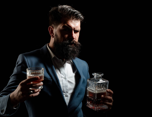 Bearded and glass of whiskey. Man Bartender with beard holds glass brandy. Alcohol concept. - Фото, изображение