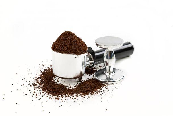 Schwarz-silberner Kaffeefilter hoch aufgetürmt mit Boden, der neben einem Stampfer sitzt, der am Ende steht - Foto, Bild