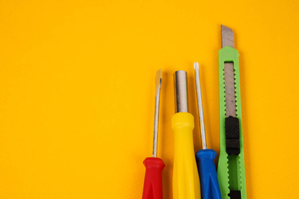 papíráru kés csavarhúzók és építőipari szerszámok sárga háttér berendezések javítási ipar - Fotó, kép
