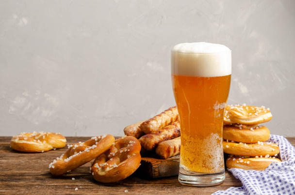 Oktoberfest alimentos, pretzels bavarianos con vaso de cerveza sobre fondo de madera rústico viejo - Foto, imagen