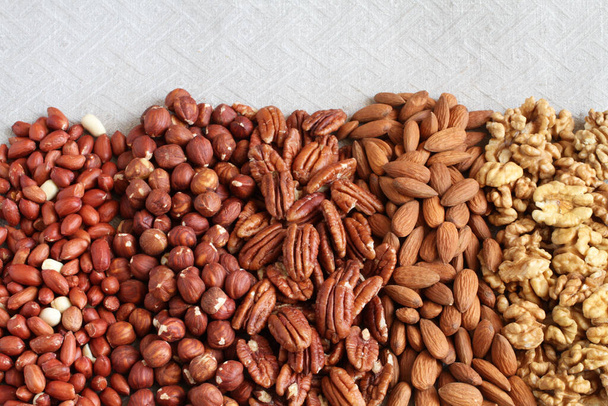 Raw peeled peanuts, hazelnuts, pecans, almonds and walnuts on a linen cloth. Closeup. Macro - Photo, Image