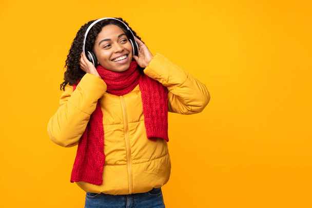 Africká americká dáma ve sluchátkách poslech hudby přes žluté pozadí - Fotografie, Obrázek