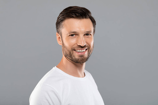 Handsome middle-aged caucasian man smiling at camera on grey - Photo, Image