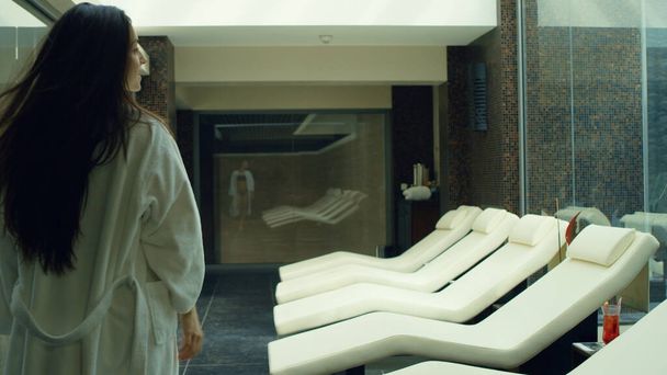 Сексуальная женщина снимает халат в спа-центре. Красивая девушка отдыхает на шезлонге. - Фото, изображение
