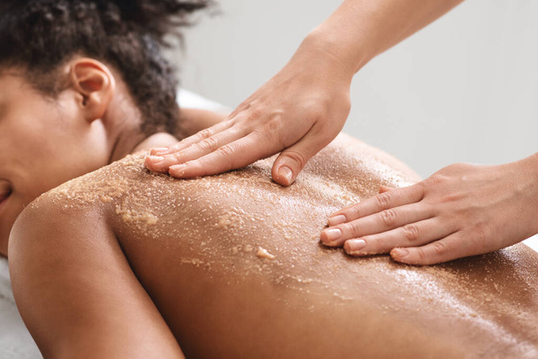 Afroamerikanerin schrubbt im Wellness-Salon die Haut - Foto, Bild