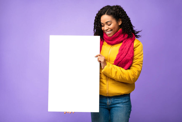 Señora negra posando con tablero de papel en blanco sobre fondo púrpura - Foto, Imagen