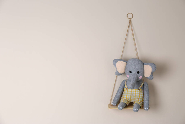 Shelf with cute toy elephant on beige wall, space for text. Child's room interior element - Fotografie, Obrázek