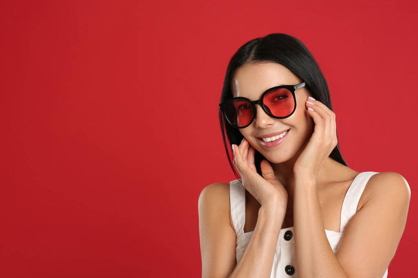 Beautiful woman wearing sunglasses on red background. Space for text - Foto, immagini